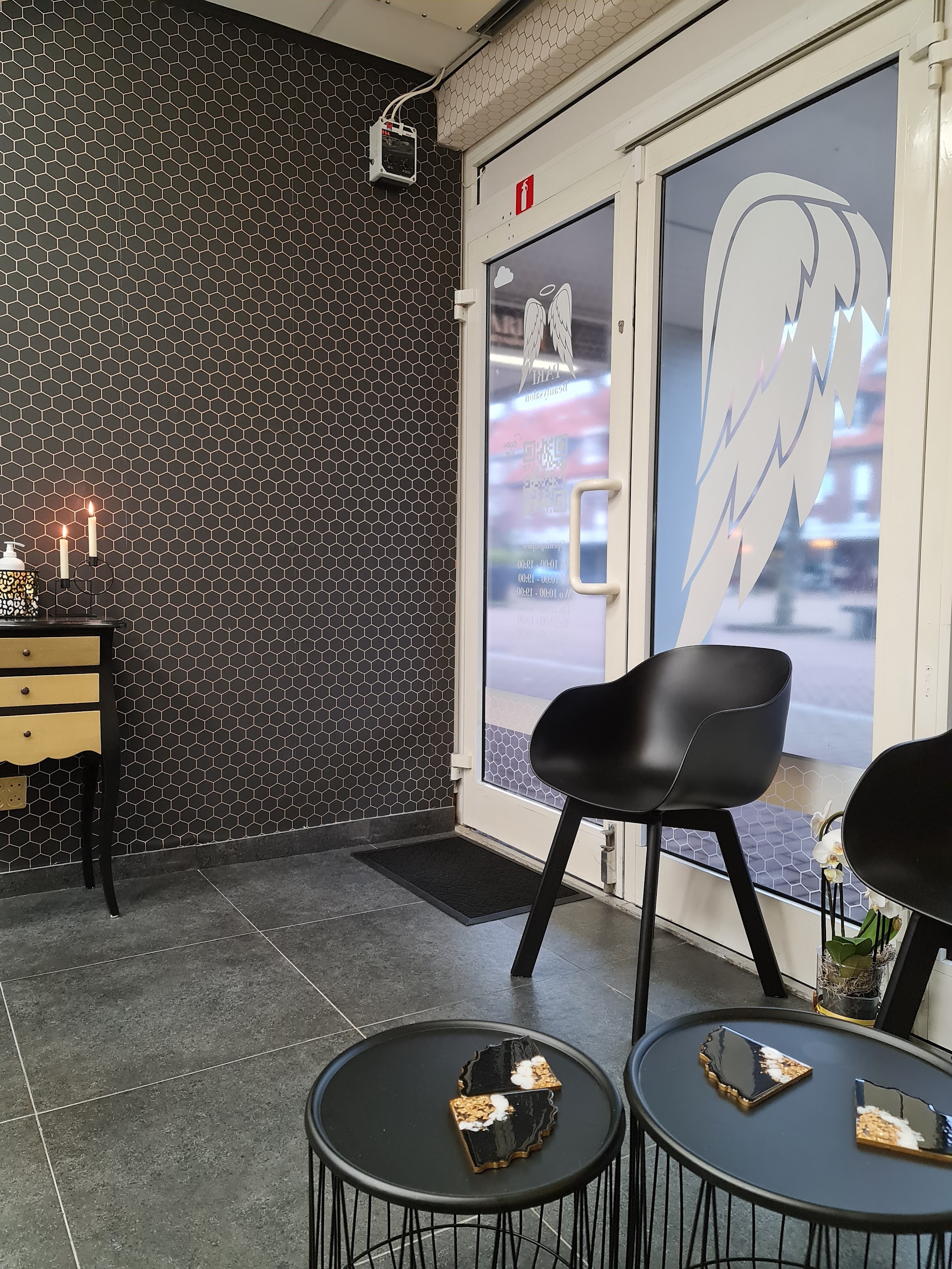 De entree van de salon: zwarte stoelen, bijzettafels en de glazen deuren met witte vleugels